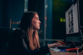 Žena s dlouhými vlasy sedí při práci před zapnutým počítačovým monitorem