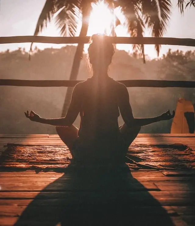 Silueta ženy při meditaci za východu slunce jako symbol zklidnění a psychické pohody